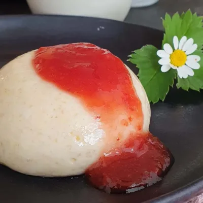 Grießflammerie auf Teller gestürzt und mit Erdbeersoße angerichtet