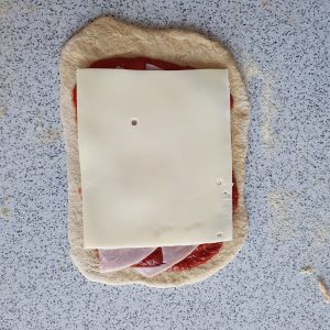 Teigfladen mit Schinken und Käse belegt