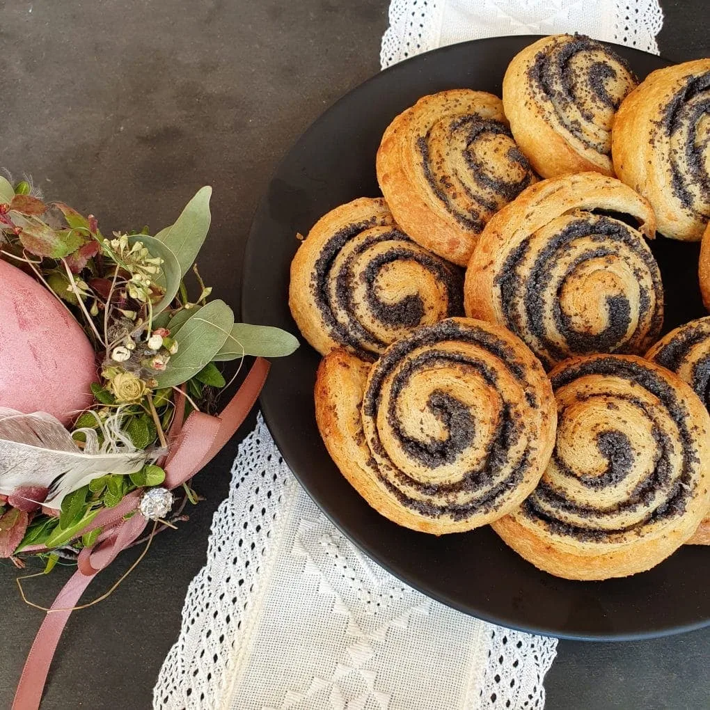 Mohnschnecken auf schwarzem Teller und weißem Tuchuf dem Tisch