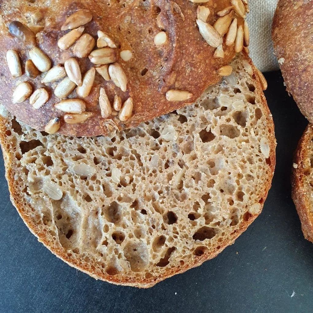 Brötchen mit Sonnenblumenkernen von oben auf schwarzem Grund