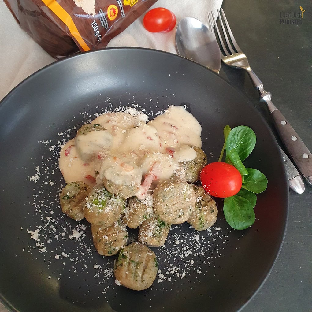 Gnocchi mit Emmer und Spinat auf einem schwarzen Teller mit Coctailtomate und Ackersalat