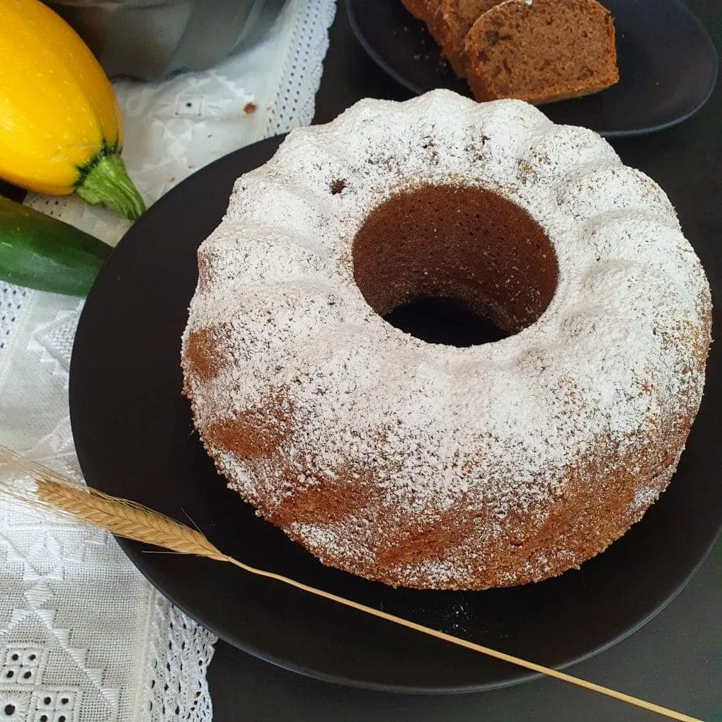 Rührkuchen, oben weiß auf schwarzem Teller, daneben eine Getreideähre
