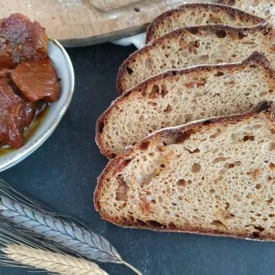 drei Scheiben Urkornbrot Sommer mit Getreideähren und getrockneten Tomaten