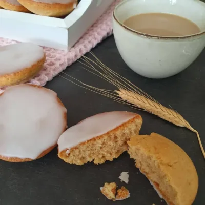 Amerikaner mit Zuckerglasur auf schwarzem Tisch und Kaffeetasse daneben