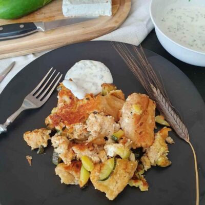 Zucchini Schmarrn mit Joghurt Dipp auf schwarzem Teller angerichtet