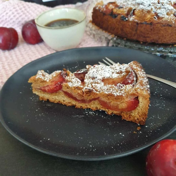 Pflaumenkuchen mit Streusel auf schwarzem Teller