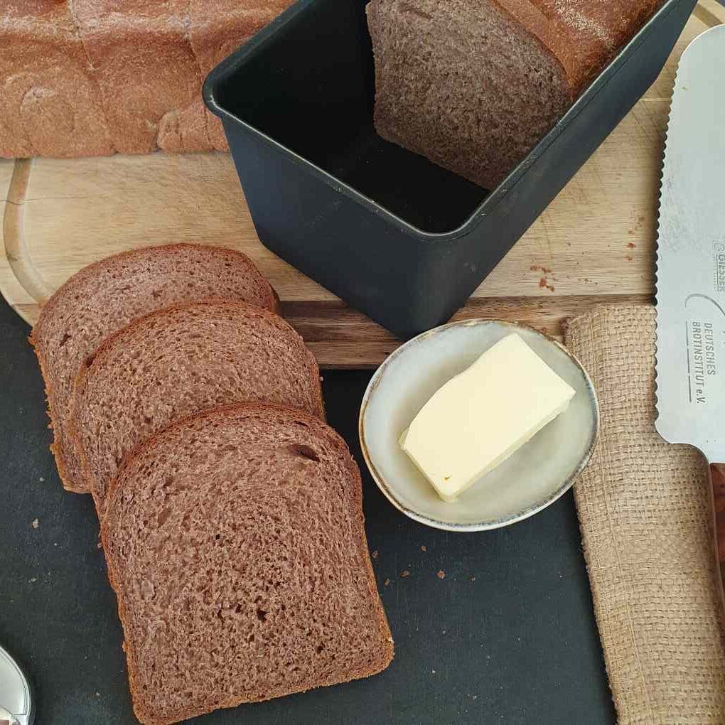 Vollkorntoast mit Rotkornweizen drei aufgeschnittene Brotscheiben mit Toastbrotform daneben
