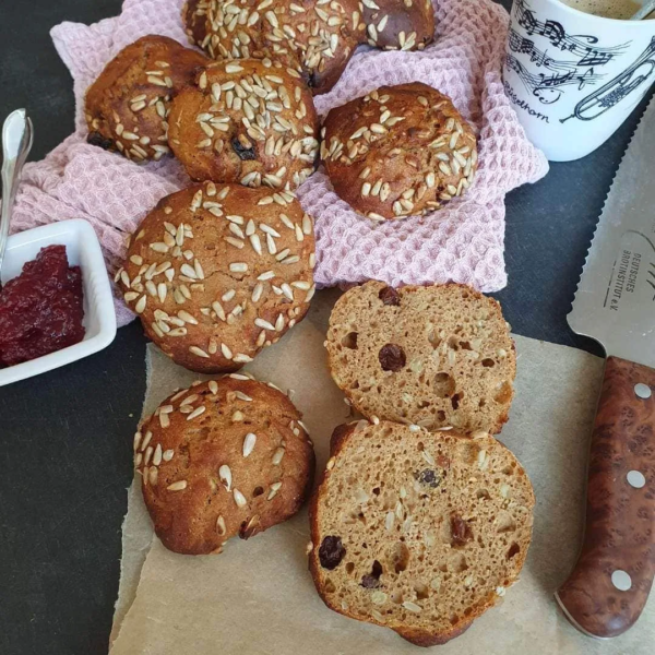 Brötchen Frühstücksgezwitscher mit Rosinen. Aufgeschnitten auf dem Tisch mit Kaffee und Marmelade