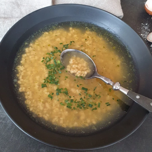 Riebelesuppe im Schwarzen Teller servierfertig angerichtet mit Schnittlauch und Löffel