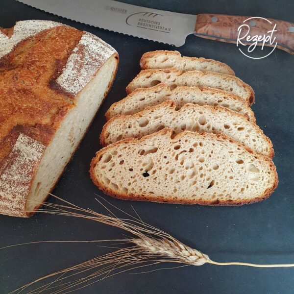 aufgeschnittenes Brot Khorasan mit Quark ohne Hefe mit Deko auf schwarzem Brett