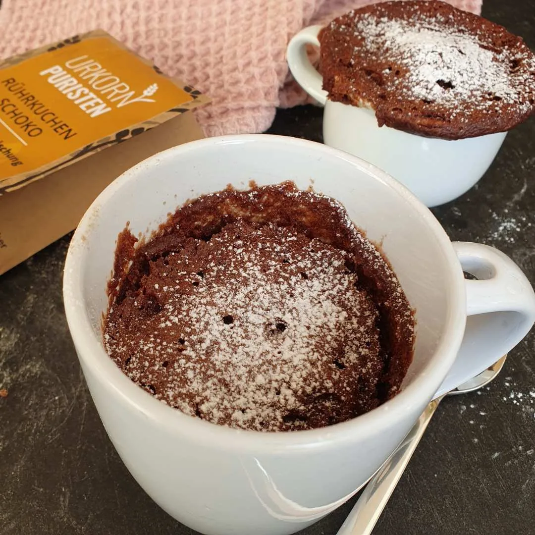 zwei Stück Tassenkuchen Schoko fertig gebacken. rose Dekotuch und Löffel