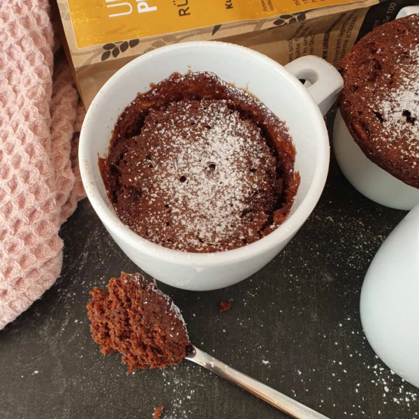 Tassenkuchen Schoko gebacken mit einem stück auf dem Löffel. Dekotuch und Produktpackung