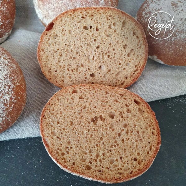 Einkornbröchen Version II - einfacher aufgeschnitten mit der Schnittfläche nach oben. Schwarzer Untergrund, graues Tuch