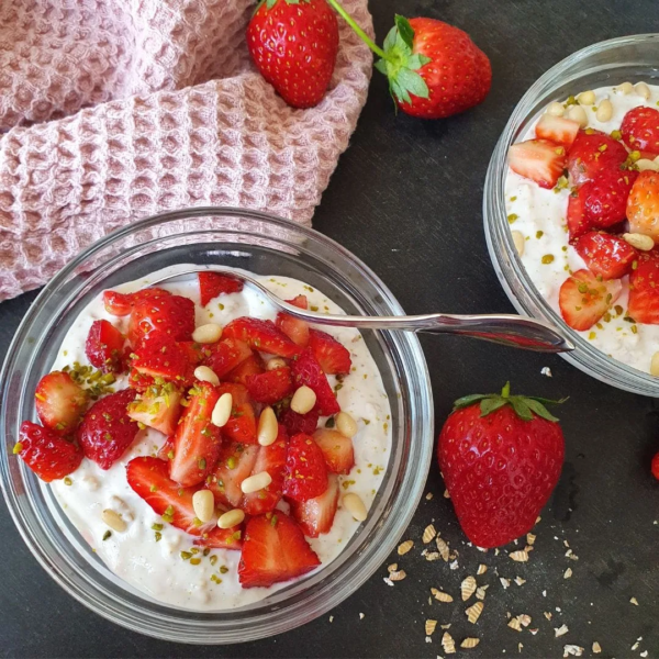 Erdbeer Urkorn Overnight von oben fototgrafiert. Getreideflocken, Erdbeeren und rosa Tuch als Deko daneben