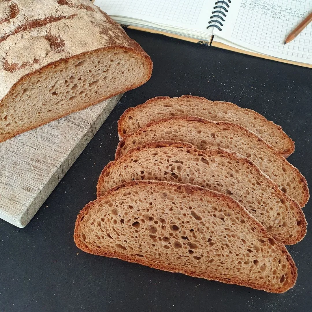 Urkorn Dreierlei aufgeschnitten auf schwarzem Tisch. Teil eines Notizbuches daneben