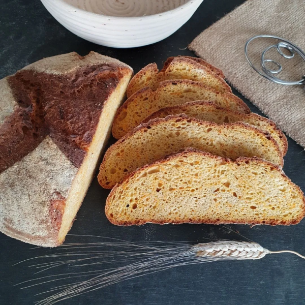 Urkornbrot Khorasan Karotte. aufgeschnittene Scheiben liegen auf schwarzem Tisch