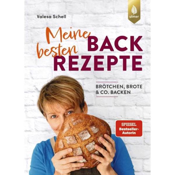 in dem Buch meine liebsten Backrezepte hat Beststeller Autorin Valesa Schell ihre besten Brot- und Brötchenrezepte zusammengefasst. Auf dem Buchcover ist Valesa Schell zu sehen. Sie steht vor einer weißen Backsteinwand und verdeckt ihr Gesicht zur Hälfte mit einem Brotlaib.