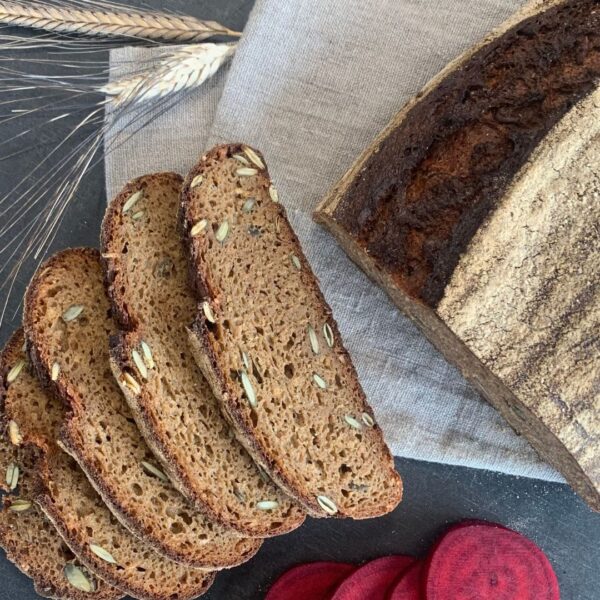 gesundes Vollkornbrot aus Brotbackmischung Buttermilchkruste. Wurzelkraft mit Kürbiskernen und Roter Beete. In Scheiben geschnitten auf Leinentuch mit Roter Bete und Getreideähren