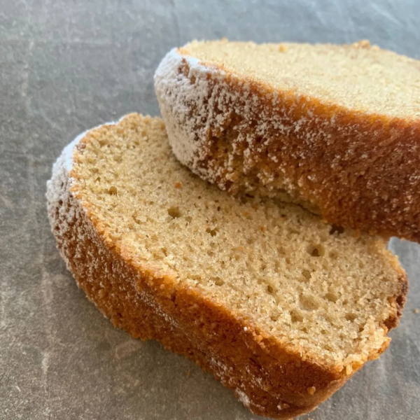 Zwei Stück Rührkuchen aus Urkorn Kuchenbackmischung liegen auf hellgrauem Tisch