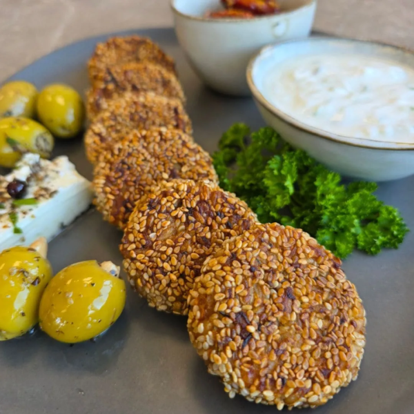 vegane Einkorn-Falafel auf einem Teller angerichtet zusammen mit grünen Oliven, Schafskäse, petersilie, getrocknete eingelegte Oliven und Kräuterquark